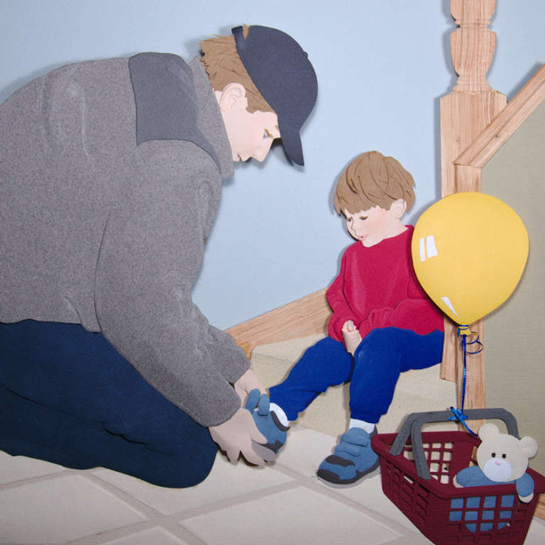 paper sculpture of father helping son put shoes on